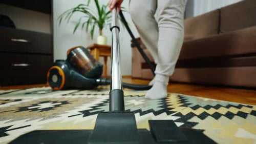 Adult Vacuuming Patterned Rug Inside Living Room