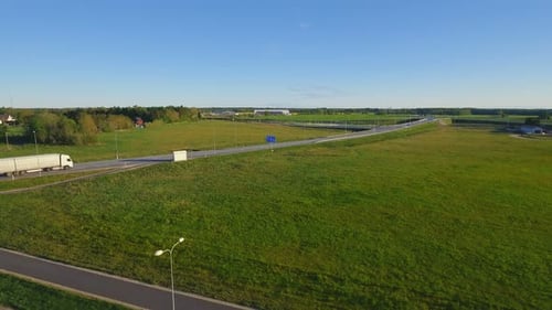 Aerial Shot of the White Semi Truck with Cargo Trailer Moving on the Highway. In the Background Wa
