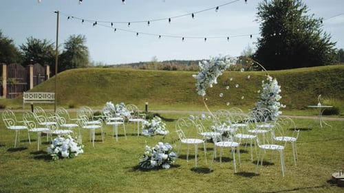 Side View of Wedding Arch Decorations of Flowers in White and Blue Colors with White Metal Chairs