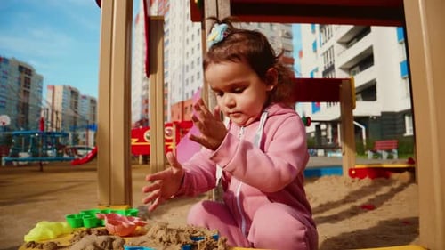 A Young Child Engaged in Creative Play with Sand at a Colorful Playground Making Shapes and Enjoying
