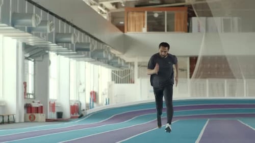 Determined Athlete Runs on Indoor Track with Prosthetic