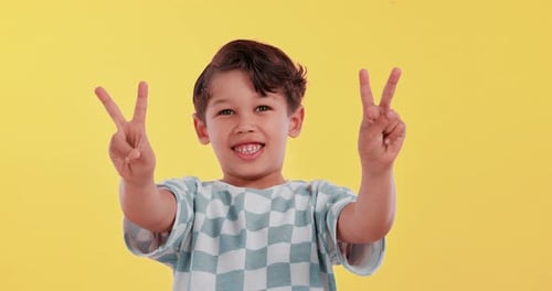 Boy, child and peace sign with smile in studio, face and choice with fashion by yellow background