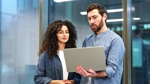 Business Colleagues Discuss Project Man Showing Information on Laptop to Female Coworker in Office