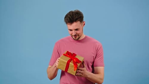 Young Man Receives Gift Box for Holiday and Examines Package