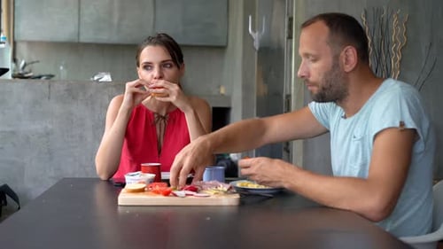 Couple eating breakfast at table indoors, morning light