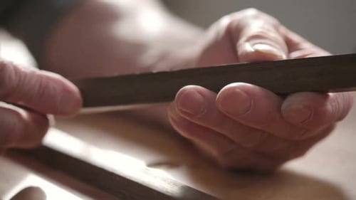 Carpenter in calgary Canada examines wood piece in workshop with dedication