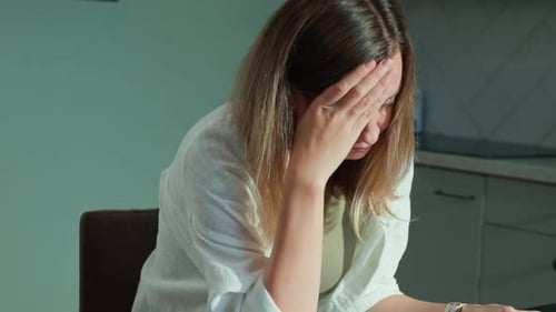 Stressed Woman Covering Her Face with Hands Over Unpaid Bills