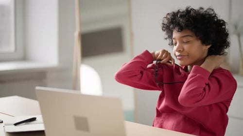 Tired Business Woman Sits Chair at Table in Home Office Doing Warm Up Stretches Massages Neck in