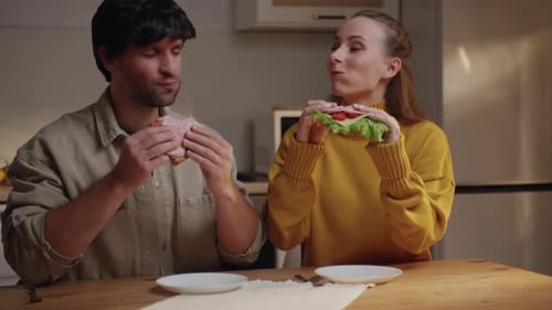 Smiling Couple Enjoying Sandwiches at the Kitchen Table