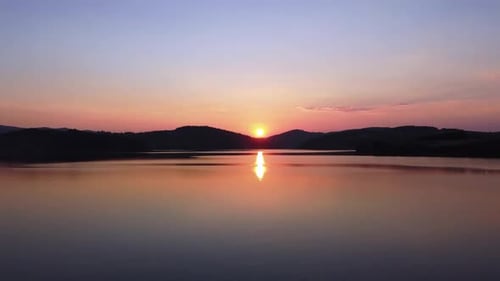 Couple hugging by the lake during sunset; aerial drone shot