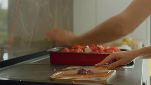 Woman crushes garlic on a chopping board in a bright kitchen setting