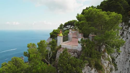 Person enjoying the view from a terrace on cliff of Capri . Woman meditates over the sea on the rock
