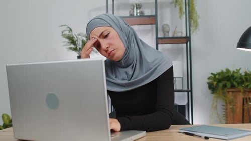 Woman Typing on Laptop Massaging Temples