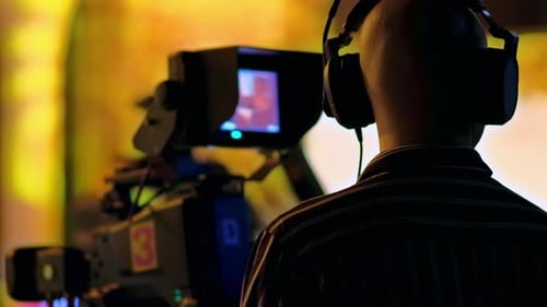 Cameraman Wearing Headphones Films on Professional Camera