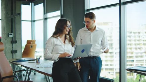 Business Professionals Discuss Project Details in Modern Office with City Views During Daytime