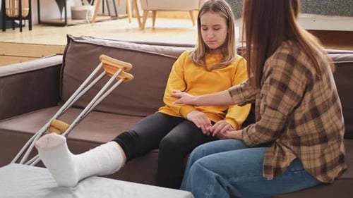 Teenage girl with broken leg comforted by woman