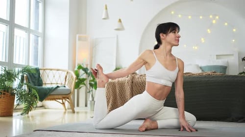 Woman Practices Yoga in a Light Bedroom