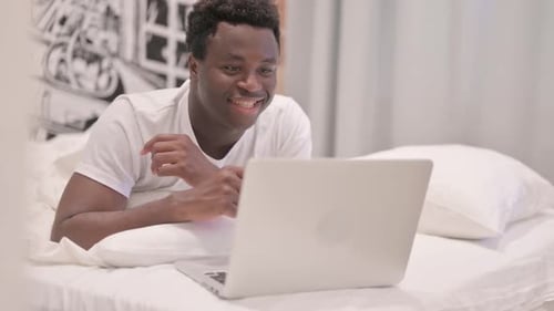 Man Lying on Bed Video Calling With Laptop