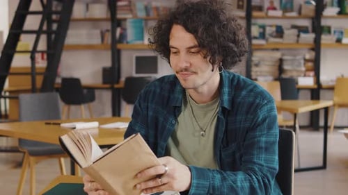 Young Man Student Reading a Book in the Library or Classroom Interested Reading a Book Student in a