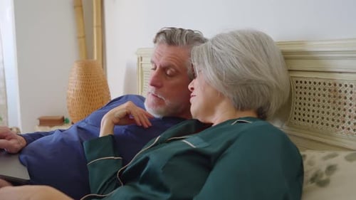 Senior Couple Enjoying Laptop in Bed Together