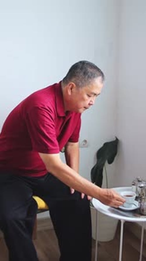 Elderly asian man enjoying warm cup of tea in cozy setting