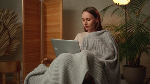 Woman Covered in Blanket Uses Laptop