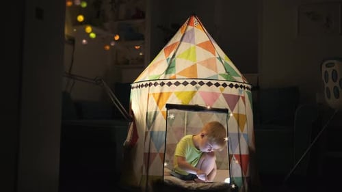 Boy Playing on Tablet in a Tent at Night