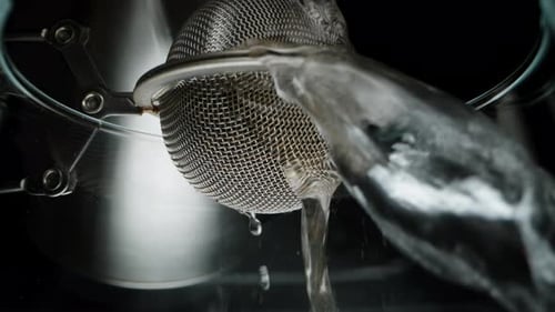 Making tea, a metal strainer inside which tea leaves are poured with boiling water. Macro view.