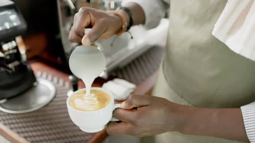 Barista Pouring Milk Into Cup of Coffee