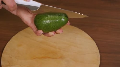 Person Cutting Fresh Green Avocado with a Knife