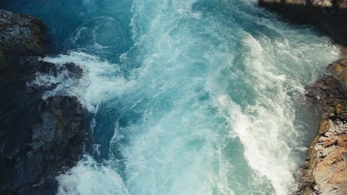 Static camera of a beautiful aqua blue river with raging white water rapids. Incredible cliffs frame