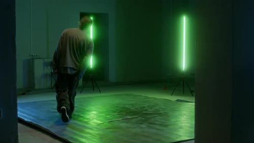 Man Breakdancing in Warehouse with Green Neon Lights