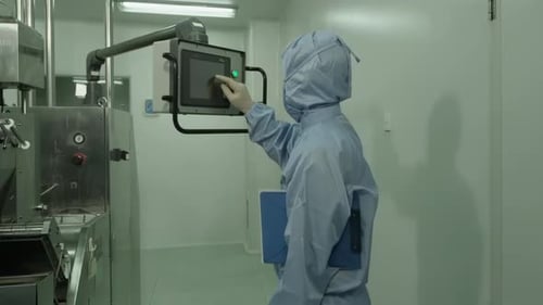 Un chimiste d'atelier en vêtements de protection travaille avec un grand mélangeur planétaire en laboratoire