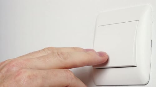 Mão humana desligando o interruptor de luz elétrica