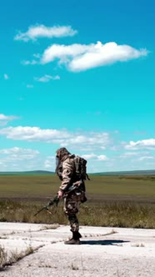 A Lone Tired Soldier Walks Along an Old Concrete Road Against a Blue Sky