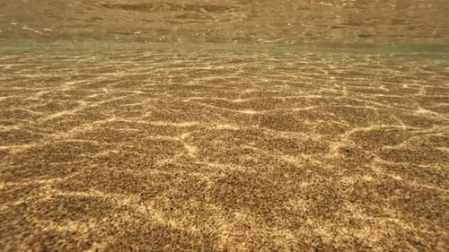 El reflejo de la luz solar de las olas del océano brilla en la arena, patrón natural