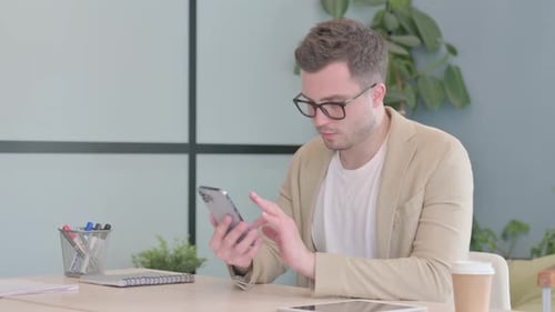 Young Businessman Using Smartphone at Work