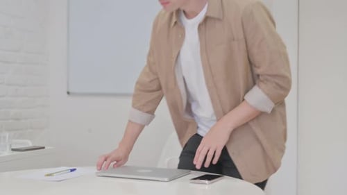 Young Adult Opens Laptop at White Office Table