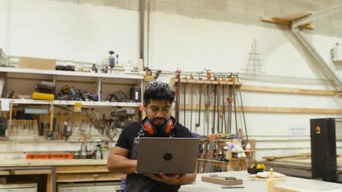Carpenter Planning on Laptop in Woodshop
