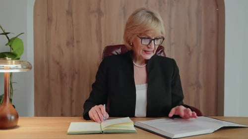 Businesswoman Taking Notes While Reviewing Documents