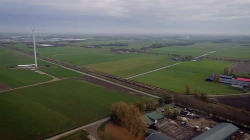Zug in Helmond Crossing Windturbine bei bewölktem Wetter in den Niederlanden.