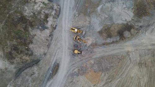 Aerial circle shot of huge industrial sand mining area with construction site vehicles.