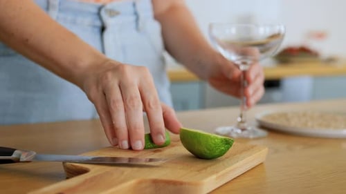 Woman cuts lime and prepares cocktail glass