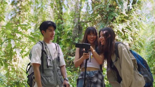 Grupo de mochileiros asiáticos se divertindo viajando juntos pela floresta.