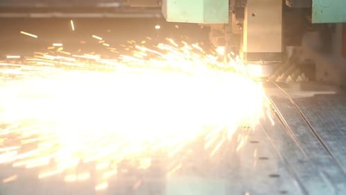 Beim Laserschneiden von Metall streuen sich helle Funken. Laserschneidanlage