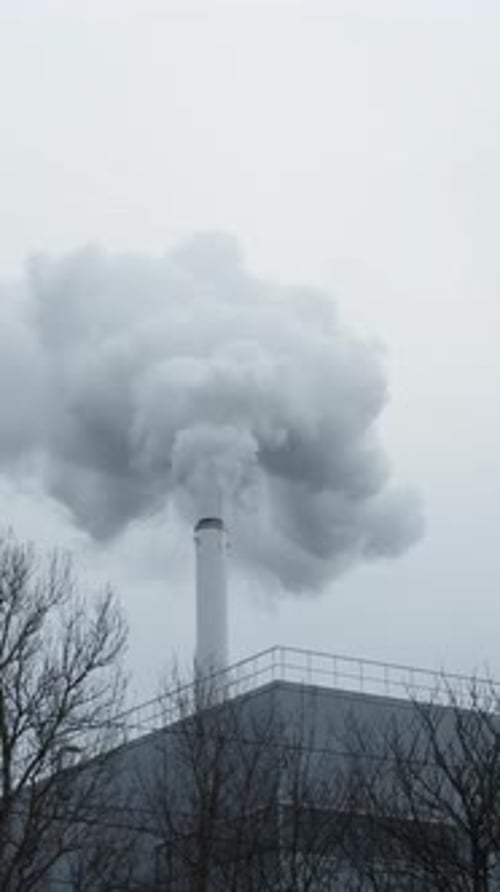 Smoke Billowing From Chimney on Building Polluting Sky