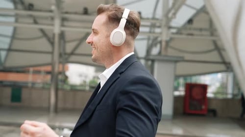 Man in Suit Walks and Listens to Headphones