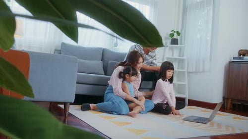 Азиатская семья с детьми использует ноутбук дома