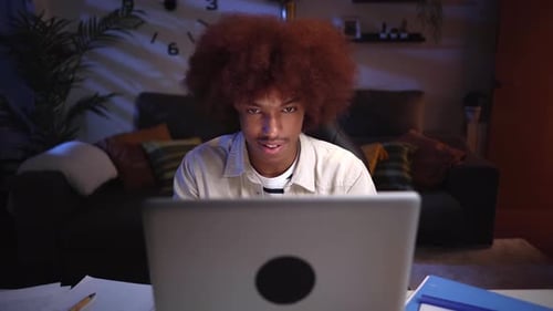 Young Adult Using Laptop at Night Indoors