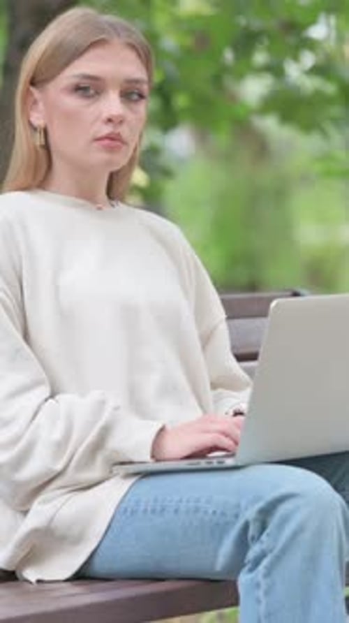 Woman Sits on Bench Working on Laptop